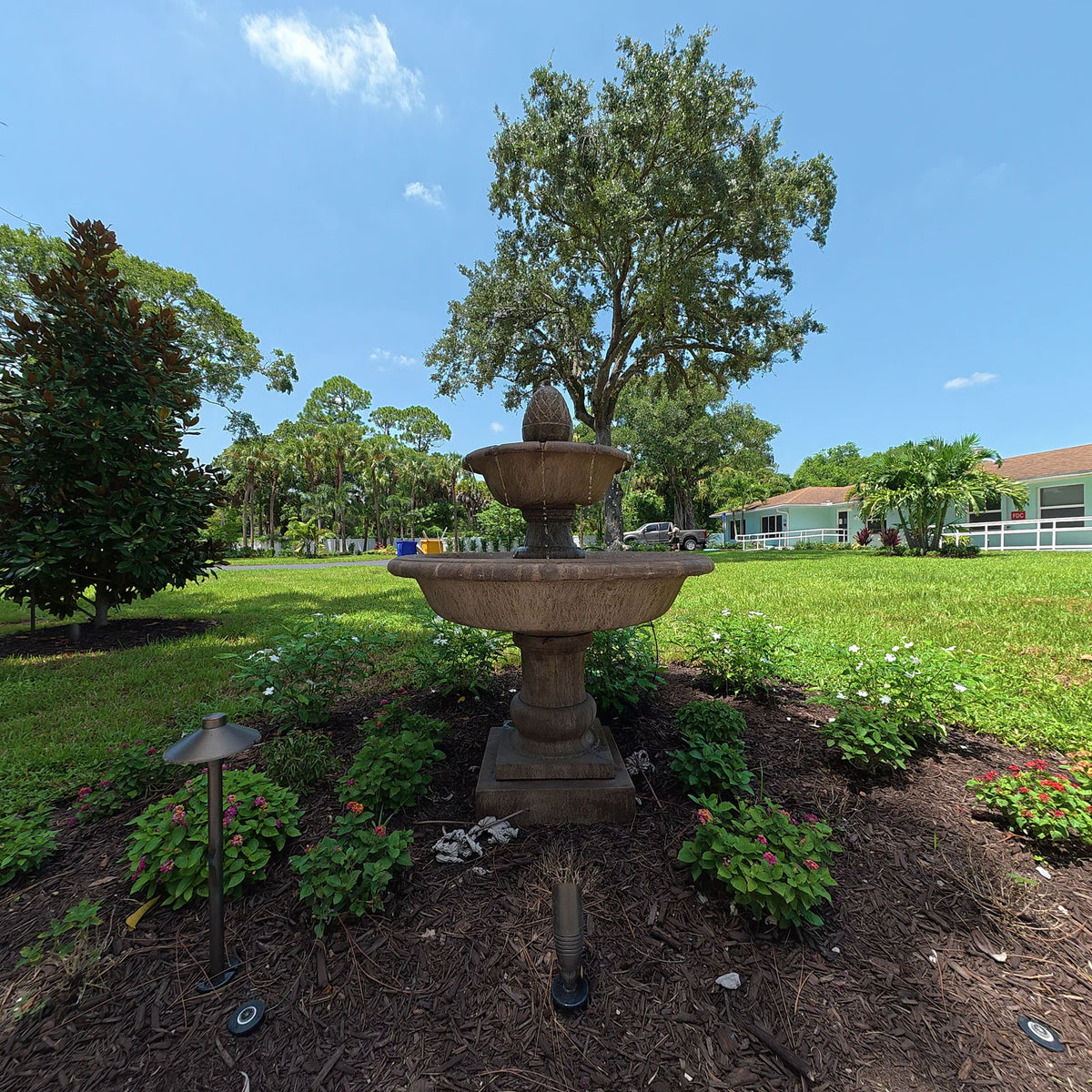 Wiltshire Fountain installed as a centerpiece in a landscaped garden with flowering plants