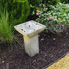 Andra cast stone fountain with bubbling water surrounded by roses and lush garden landscaping