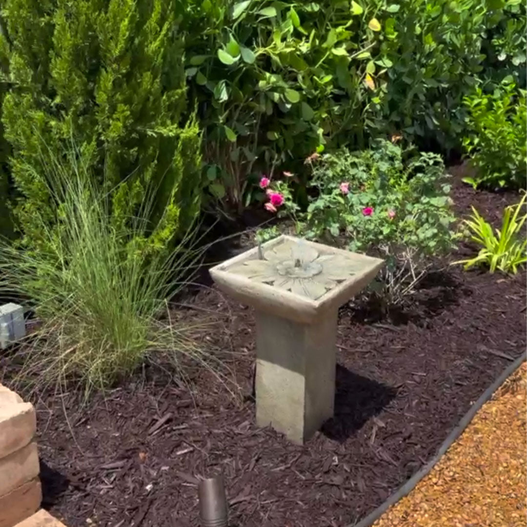 Andra Fountain installed among ornamental grasses and flowering plants in a landscaped garden bed