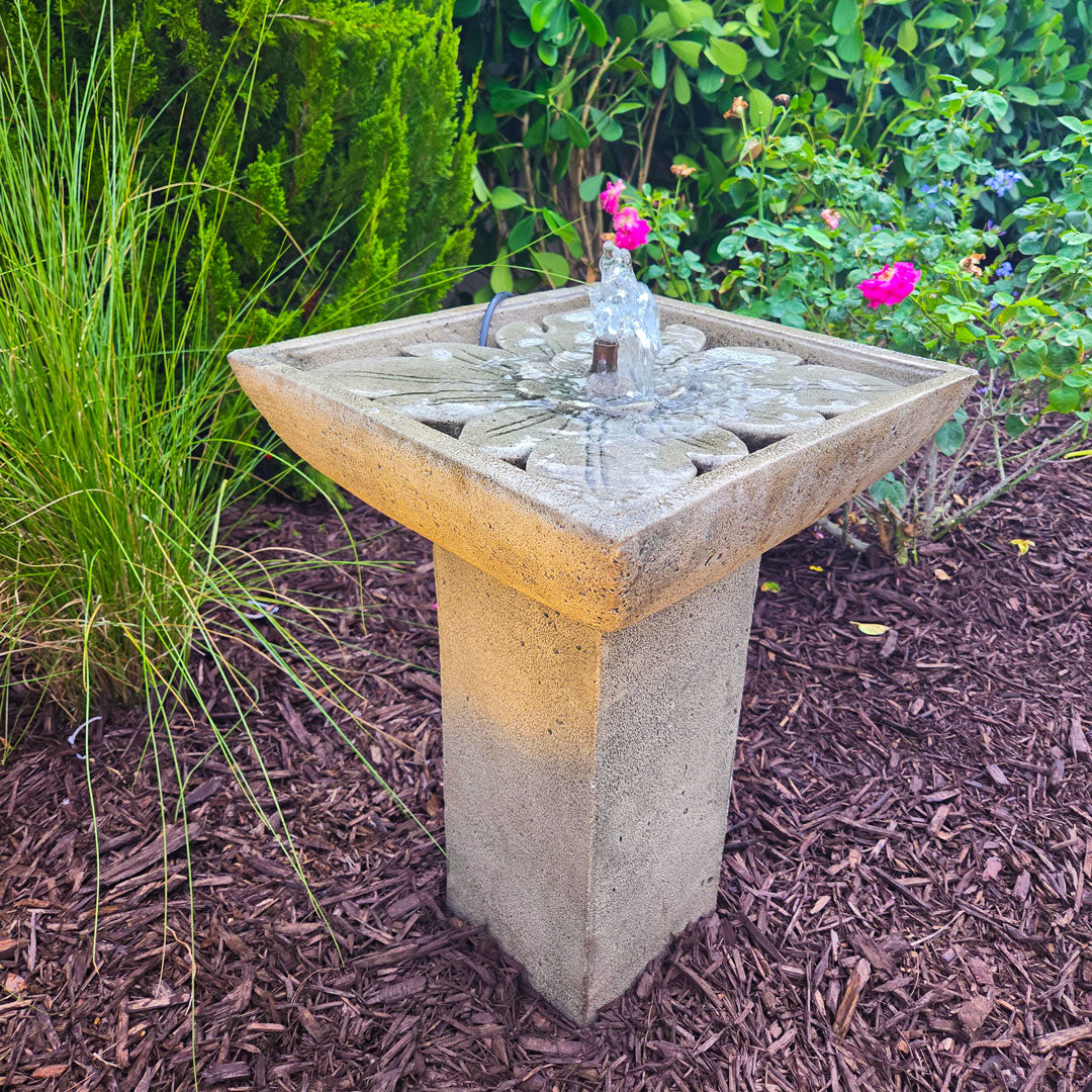 Andra Fountain with bubbling water and floral basin detail surrounded by lush garden landscaping