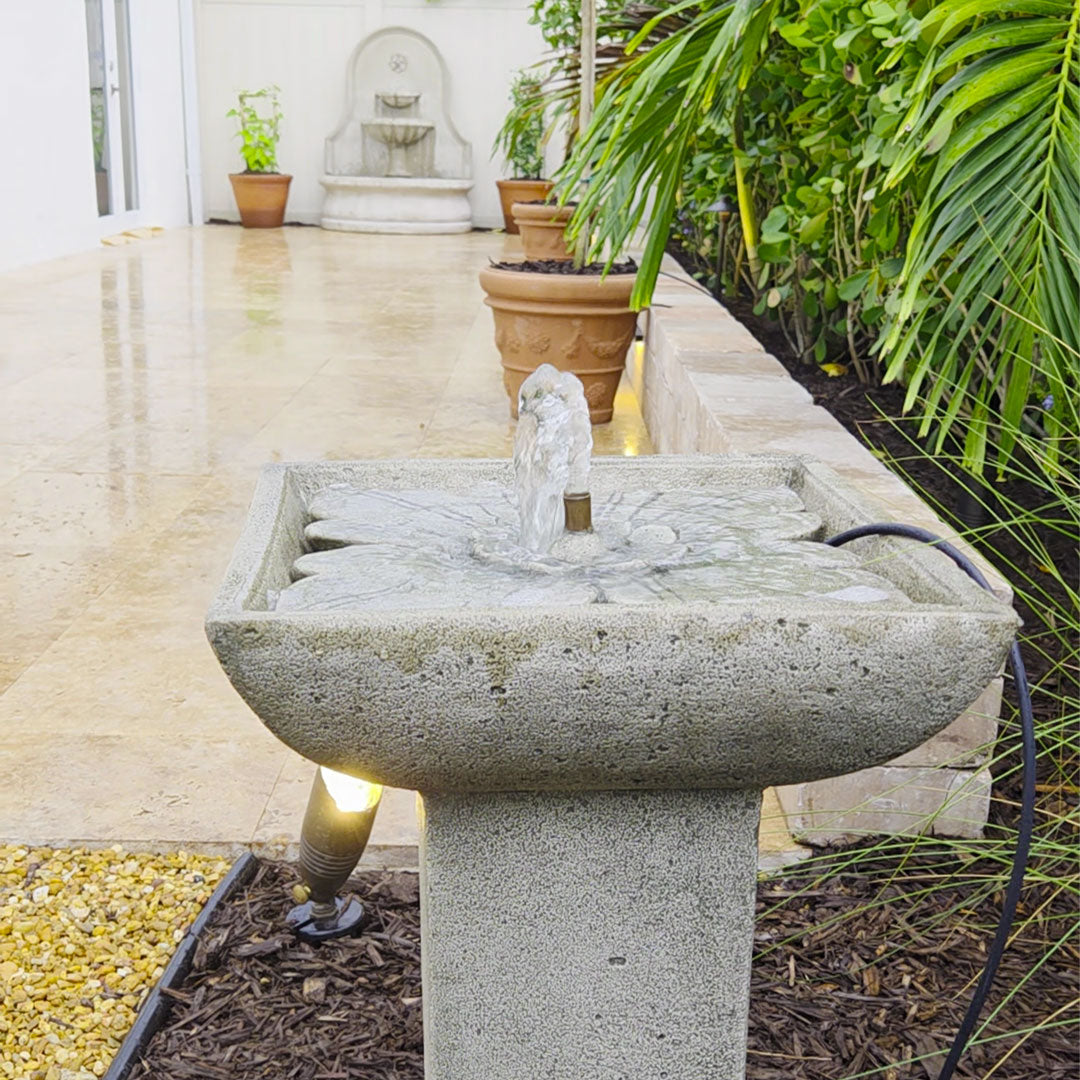 Close view of the Andra Fountain with bubbling water beside a tropical garden walkway