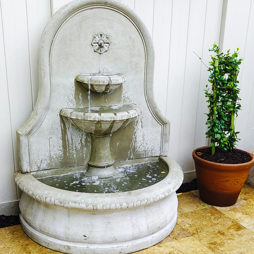 Close view of the Estancia cast stone fountain showing cascading water, tiered bowls, and decorative back panel