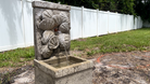 Angled view of the Nassau Wall Fountain showcasing the handcrafted cast stone seashell design and cascading water