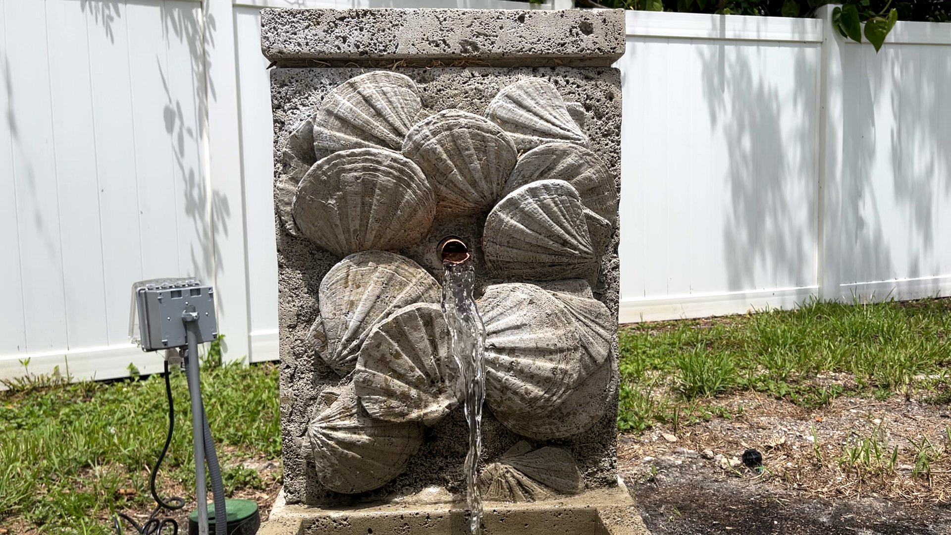 Front view of the Nassau Wall Fountain featuring a copper water spout and handcrafted cast stone seashell wall
