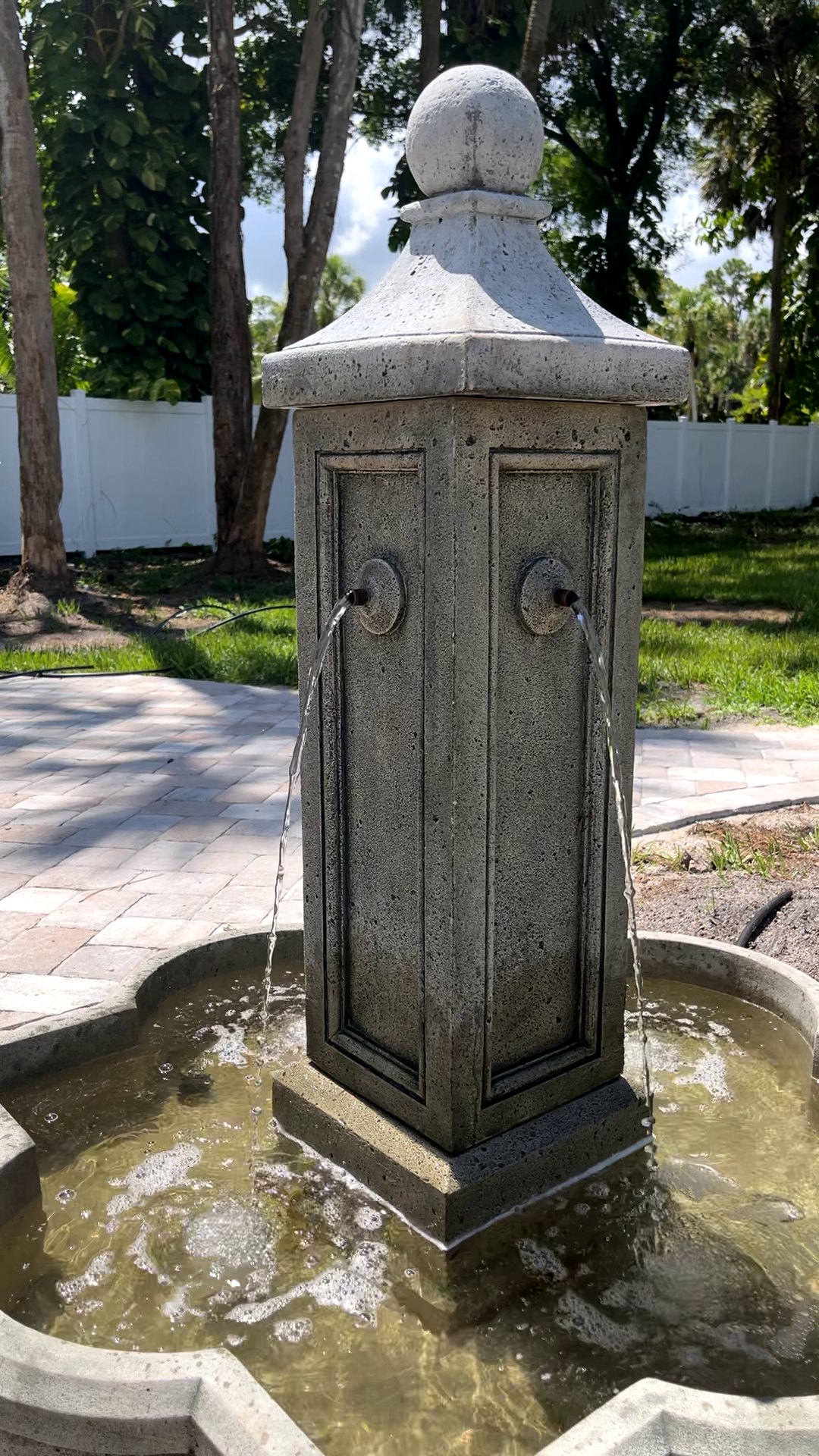 Provence Fountain showcasing its cast stone column with four flowing water spouts in an outdoor garden setting